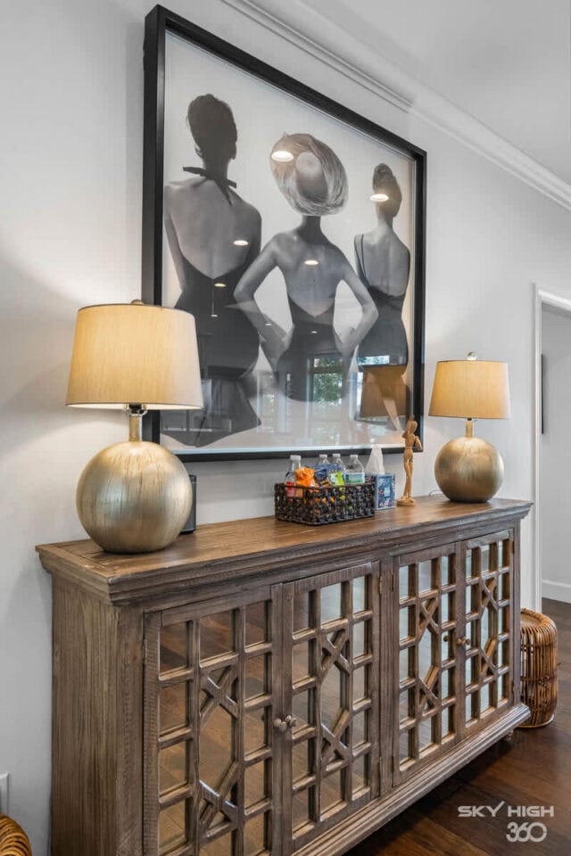 Elegant wooden sideboard with decorative lamps and artwork in a cozy vacation rental interior.