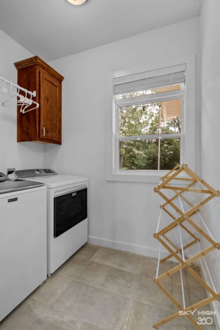Small laundry room with washer, dryer, and window in Black Bear Cabin rental.