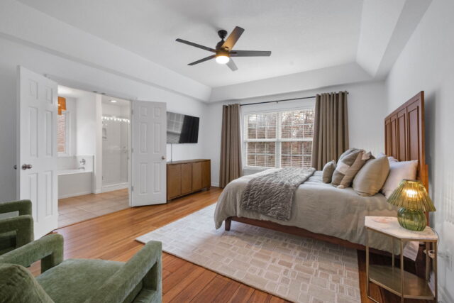 Cozy bedroom with large window, ceiling fan, and modern decor at The Witherby Woodland Retreat.