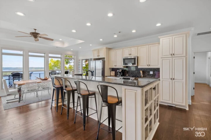 A comfortable, modern kitchen with white cabinets, granite countertops, and a view of Beaver Lake in.