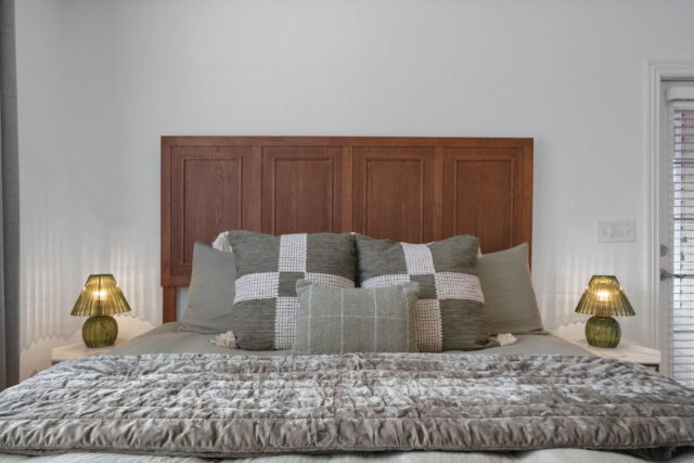 A comfortable bedroom with a wooden headboard, cozy pillows, and soft lighting in the Witherby Woodl.