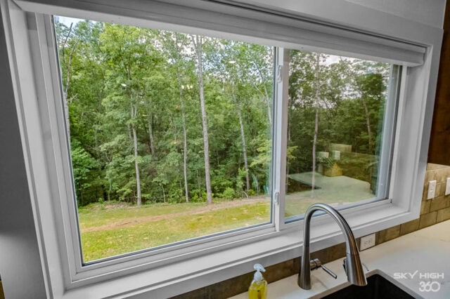 A lush green forest view from a large kitchen window at Black Bear Cabin.