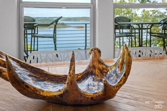 Unique wooden boat sculpture with lake view in the background, perfect for vacation rental decor.