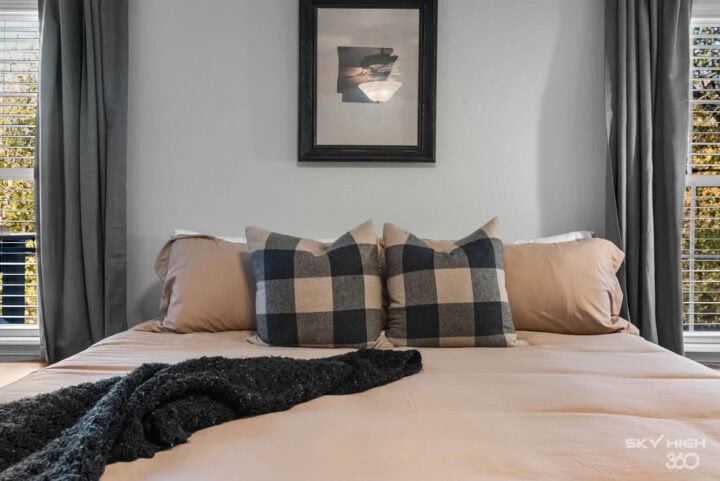 A comfortable bedroom with neutral tones and cozy plaid pillows, perfect for a relaxing stay near Oz.