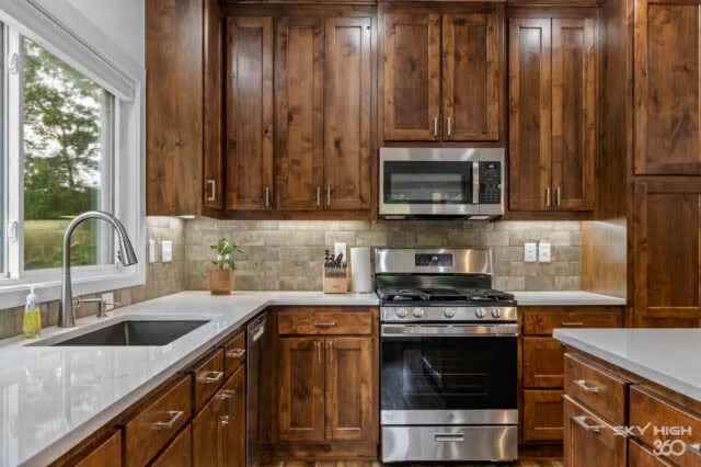 Modern kitchen with wooden cabinets and stainless steel appliances in Black Bear Cabin rental.