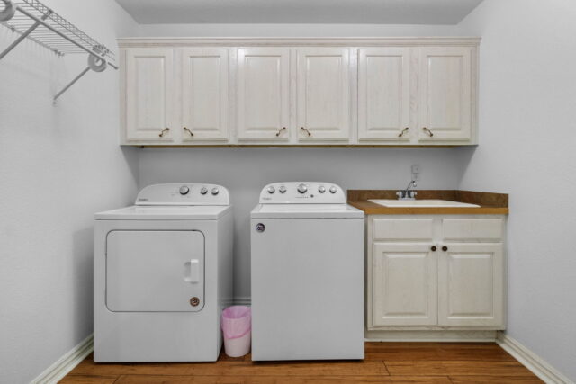 Bright laundry room with washer, dryer, and white cabinetry at The Witherby Woodland Retreat. Perfec.