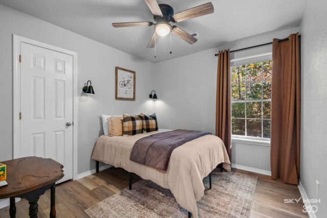 Cozy bedroom with large window, ceiling fan, and modern decor in Bella Vista retreat.