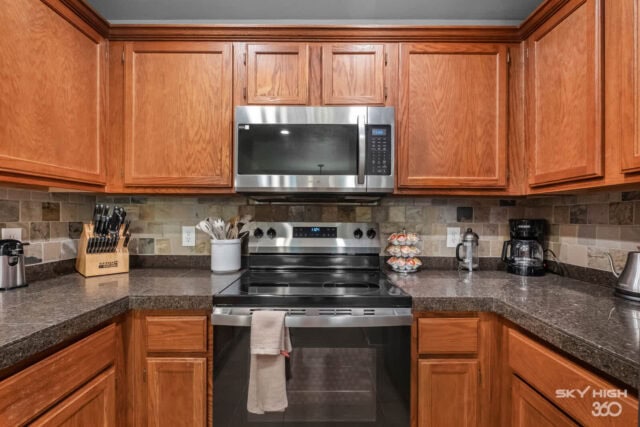 Modern kitchen with wooden cabinets, stainless steel appliances, and granite countertops.