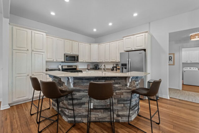 Bright modern kitchen with white cabinets, stainless steel appliances, and a stone island in the Wit.
