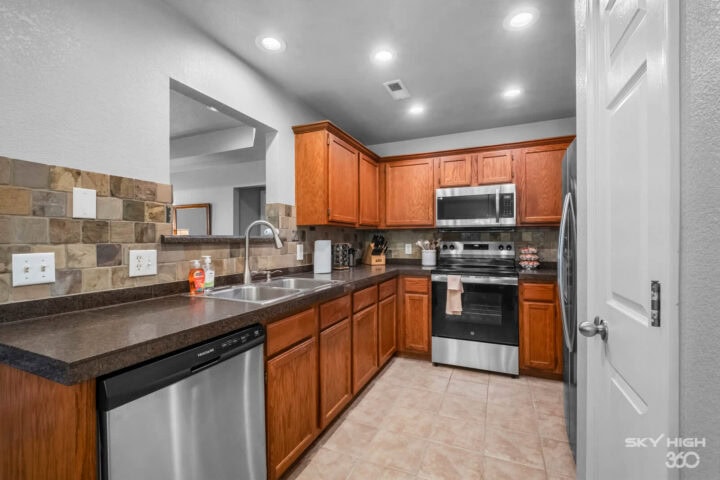 Modern kitchen with wooden cabinets, stainless steel appliances, and granite countertops in a cozy r.