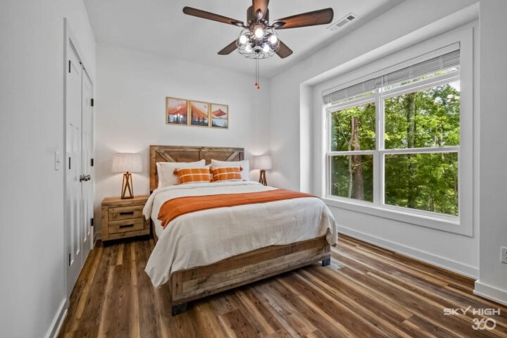 Cozy bedroom in Black Bear Cabin with large window overlooking lush forest in Bella Vista.
