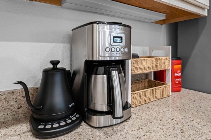 Bright kitchen coffee station with a modern coffee maker, electric kettle, and storage baskets at Th.