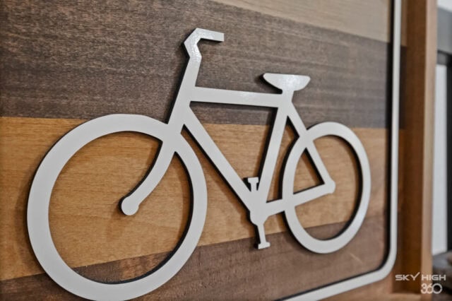 Modern white bicycle wall decor on wooden background, ideal for vacation rental home interior.