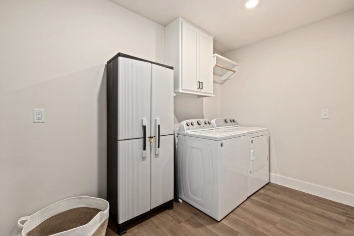 Modern laundry room with refrigerator and washer in Bella Vista vacation rental near Back 40 Trails.