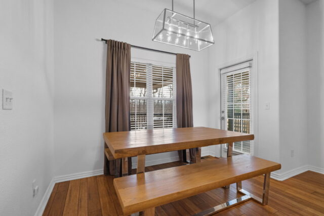 Bright dining area with wooden table and bench, natural light, and modern chandelier in the Witherby.