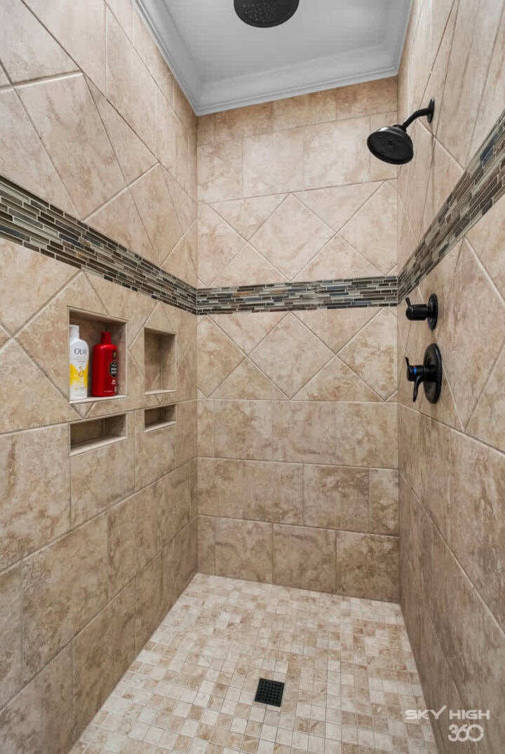 Modern beige tiled shower with built-in niche and black fixtures in Rivercliff Ridgehouse rental.