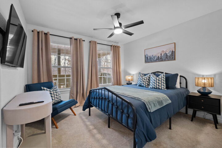Cozy bedroom with blue bedding, large windows, and modern decor at The Witherby Woodland Retreat.