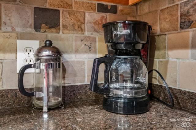 Coffee maker and French press on kitchen countertop in a cozy retreat.