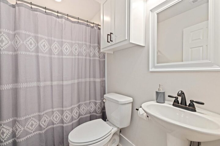 Clean bathroom with white fixtures and a patterned shower curtain at OZ Adventure Retreat near Back.