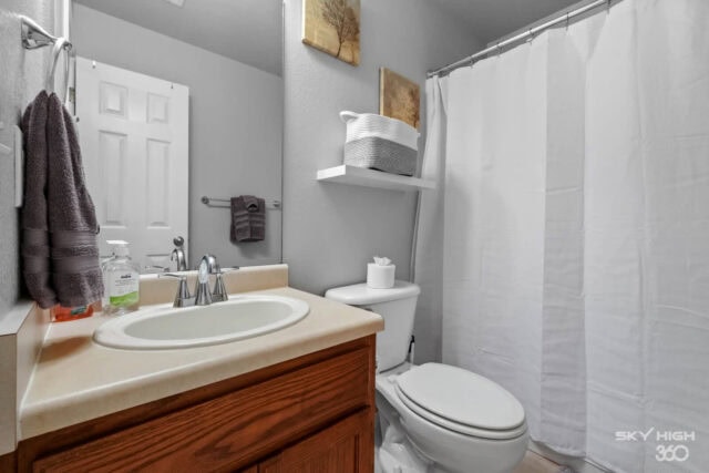 Modern bathroom with neutral decor, white shower curtain, and wooden vanity for comfortable stay nea.