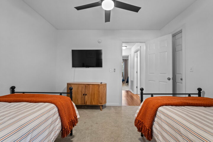 Relaxing bedroom with two twin beds, ceiling fan, and modern decor at The Witherby Woodland Retreat.