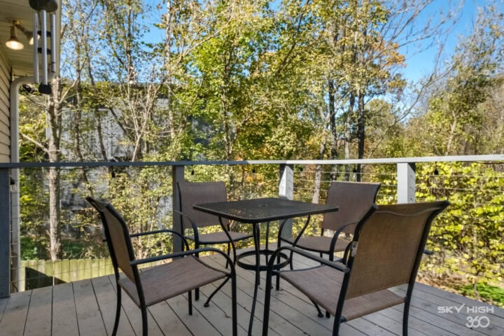 A comfortable outdoor balcony with a table and chairs overlooking lush trees and nature.