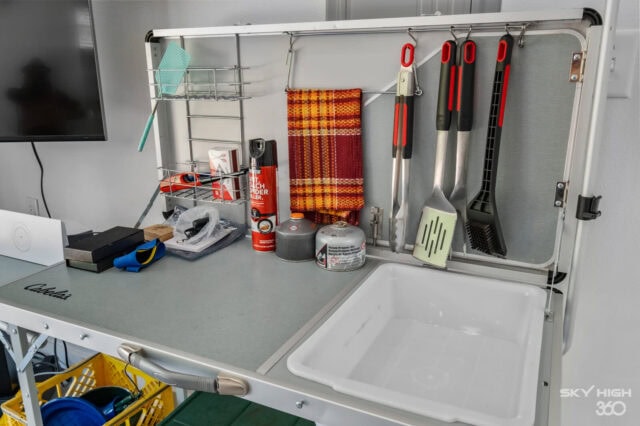 Cleaning and maintenance supplies organized on a wall-mounted rack in a vacation rental kitchen.