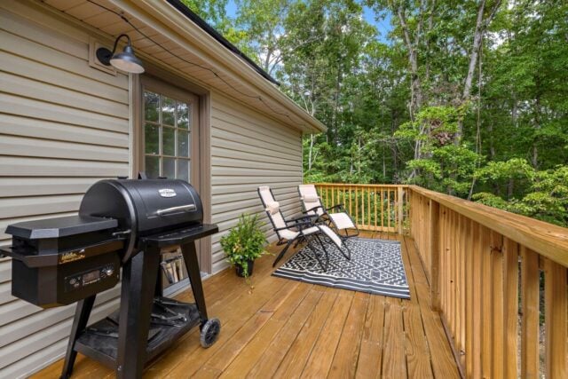 Cozy outdoor deck with grill and seating near lush forest at Bella Vista vacation rental.