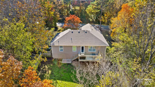 Aerial view of a cozy house surrounded by colorful fall trees in Bella Vista, Arkansas.