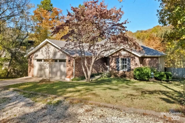 Cozy brick house with a front yard and mature trees in a peaceful suburban setting.
