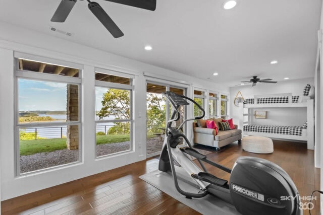 Bright living room with large windows overlooking Beaver Lake, featuring a treadmill and cozy seatin.