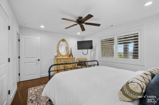 Cozy bedroom with white walls, ceiling fan, and large windows overlooking Beaver Lake in Rogers, AR.