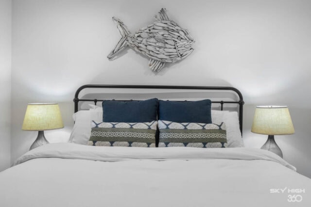 A fish-shaped wall decor above a neatly made bed with blue and patterned pillows, in a modern bedroo.