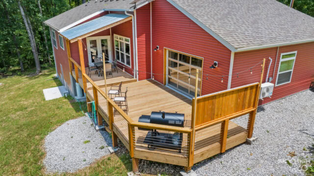 Cozy red cabin with a spacious wooden deck and outdoor grill, perfect for bike-in vacation rentals i.