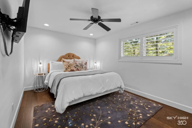 Bright, modern bedroom with white walls, large window, ceiling fan, and cozy bed in Rivercliff Ridge.