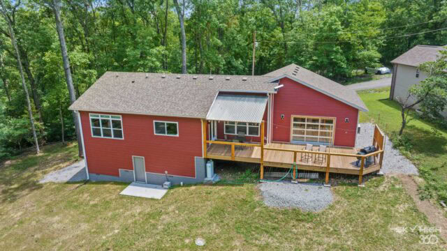 Cozy red cabin with a spacious deck surrounded by lush green trees in Bella Vista.
