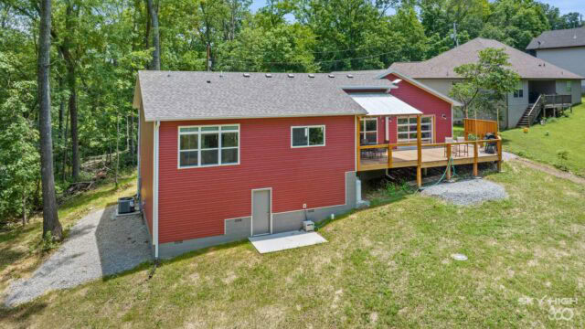 Cozy red cabin with a spacious wooden deck nestled among lush green trees in Bella Vista.