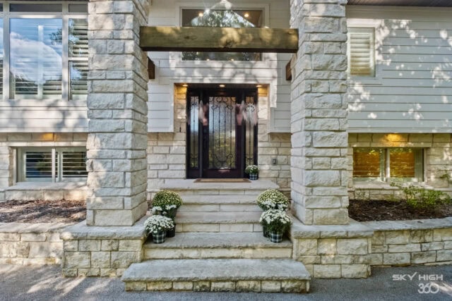Front door entrance of Rivercliff Ridgehouse with stone steps and potted plants, Rogers, AR vacation.