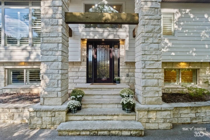 Front door entrance of Rivercliff Ridgehouse with stone steps and potted plants, Rogers, AR vacation.