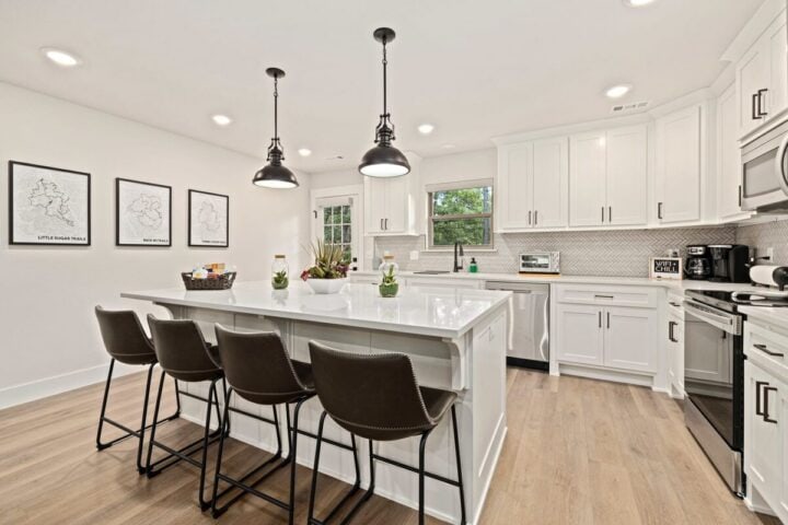 Modern white kitchen with island and black pendant lights, perfect for vacation rentals near Back 40.