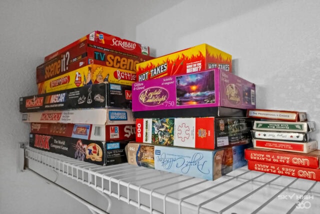 A colorful collection of board games stacked on a wire shelf in a cozy retreat setting.