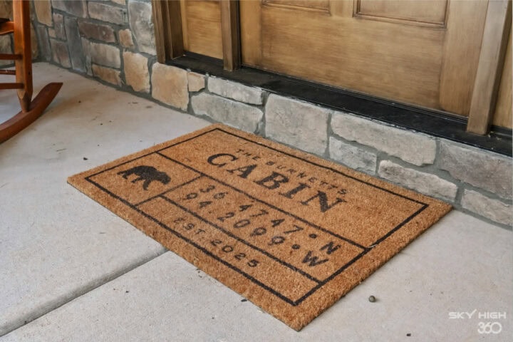 Black Bear Cabin welcome mat at front door, rustic outdoor entryway, perfect for bike-in vacation re.