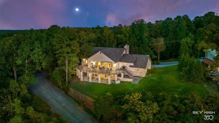 A lush riverside vacation rental home at night with scenic forest views in Rogers, AR.